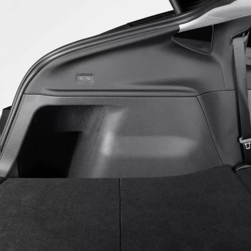 Car trunk interior showing a small seat-release button on the side panel near the cargo area edge.