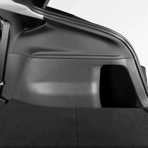 Cargo area of a hatchback with the rear seats folded and a dark carpeted floor panel visible on the left side paneling