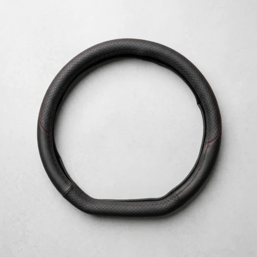 Black leather steering wheel cover, circular with red stitching, laid on a light gray surface.