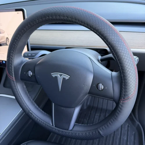 Tesla steering wheel with textured grip and red contrast stitching, centered by the logo and integrated controls on the spokes
