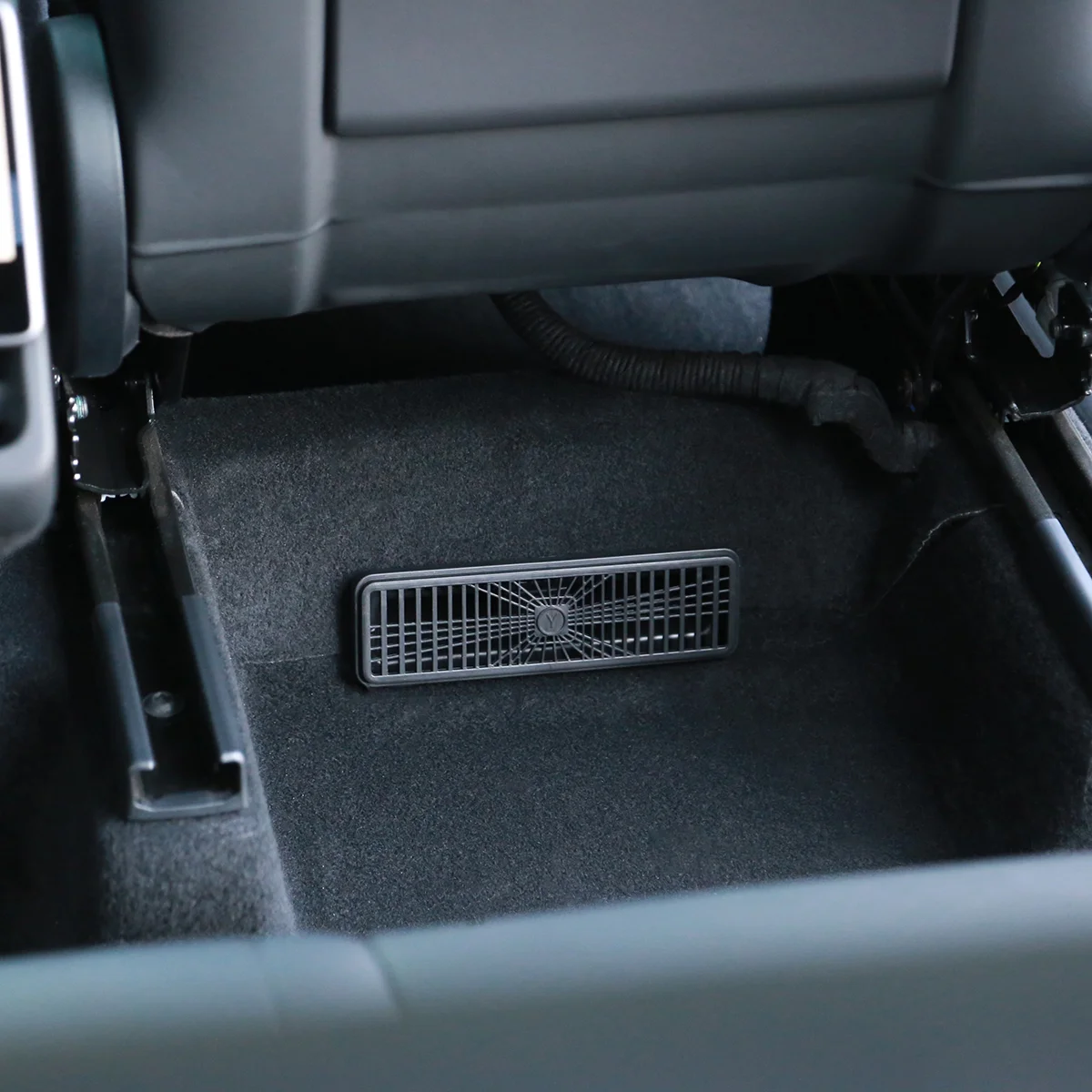 Rectangular floor vent grille in the car's footwell for climate control