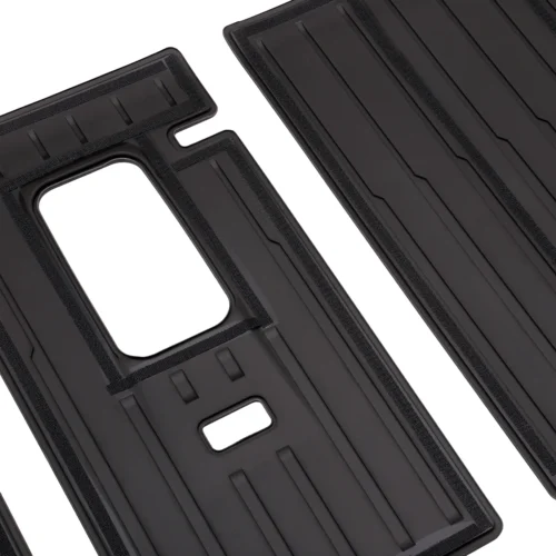 Close-up of two black plastic vehicle floor/mat inserts with raised ridges and cutouts, shown from an angled view.